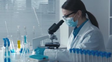 Araştırmacı, tıbbi çalışmalar ve kimyasal analizlerde istikrarın ve güvenilirliğin sağlanması için rutin analizler gerçekleştirir. Kadın işçi mikroskopla laboratuvar çalışması yapıyor. Yüksek kalite