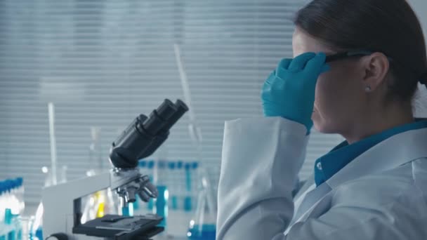 一位制药科学家对新药的安全性和有效性进行了测试 这有助于改善该大学的医疗实践 女人透过显微镜的目镜检查测试 — 图库视频影像