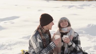 Genç bir çift güne bir kış sabahı kayak merkezinde açık bir çimenlikte bir fincan aromatik kahvenin tadını çıkararak başlıyor. Yüksek kalite 4k görüntü