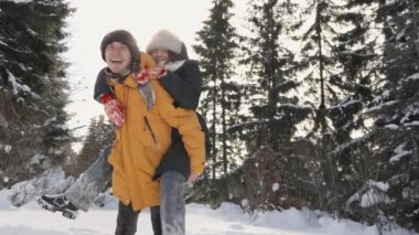 Sevgi dolu çift, kış tatilinde karla kaplı ağaçların yakınındaki karlı çayırlarda sarılıp oynayıp eğleniyor. Yüksek kalite 4k görüntü