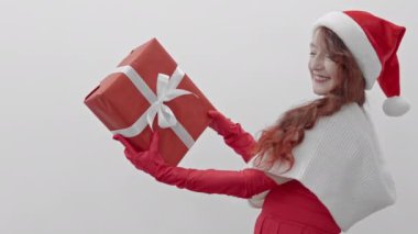 Sevgi dolu, güzel bir kadın şefkatle ve sıcaklıkla hediyeyi kucaklıyor, beyaz izole edilmiş arka planda ahenk anları ve büyük neşe yaratıyor. Yeni yıl ve Noel. Yüksek kalite 4k görüntü