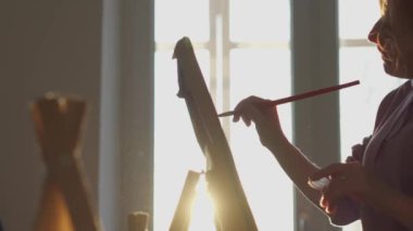 Sanatçı stüdyosunda atmosferik bir akşam. Sanatçı, stüdyosunun içinde, geleneksel sanatın sınırlarının ötesine uzanan eşsiz bir görüntü yaratıyor. Güneş ışınlarının arka planına karşı