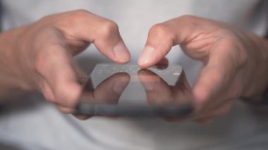 Duygusal iletişim kurma. Genç bir kadın, akıllı telefonunda mesajlaşırken duygularını emoji ve mesajlarla ifade ediyor. Akıllı telefondan mesaj yazan adam, modern iletişim.