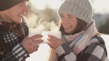 Kışın piknikte olan gençler sıcak bir içecek içer, konuşur, gülümser ve kışın ve Noel tatillerinin yeni yıl atmosferinin tadını çıkarırlar. Güneşli bir kış günü ve dinlenme. Yüksek