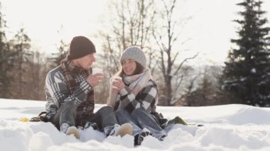 Sevgililer, sıcak içecekler ve lezzetlerin atmosfere sıcaklık ve şefkat kattığı kış pikniğini severler. Çift, karlı bir yerde oturmuş planlarını tartışırken kış kahvaltısının tadını çıkarıyor.