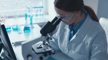 Tıp laboratuarındaki bir doktor önemli araştırmaları yönetir. Mikroskop altında gelişmiş bilimsel yöntemleri ve bilgisayardaki verilerin bolluğu birleşerek yeni veriler yaratıyor.