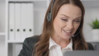 Bir kadın çağrı merkezi operatörü uzaktan çalışır, soruların etkili çözümünü sağlar ve müşterilere telefonla yardım eder. Bu, şirketin destek sisteminde önemli bir bağlantıdır.