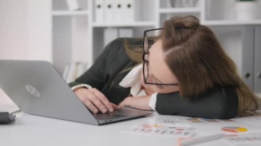 Tired businesswoman resting on desktop. Business woman fell asleep on table in front of computer. Fatigue, exhaustion, and overwork at work. Rest at the workplace and naps. High quality 4k footage