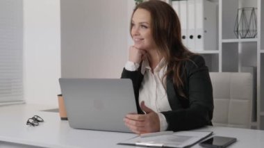 A businesswoman who turns challenges into opportunities and leads her team to victory. A successful woman smiles dreamily, happily imagines the positive results of her work. Business woman with laptop