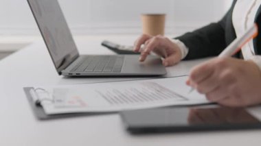 Businesswoman at home: independent and highly productive, using remote technology. Close-up of working with documents and computer in the workplace. A woman works on graphs and indicators. High