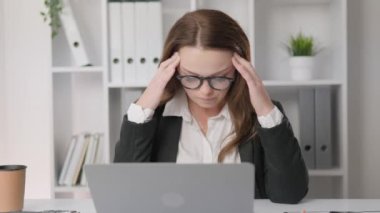 Pensive and tense woman sitting in office An office worker thinks about solving problems. The manager is upset and has a headache. Tense and tired businesswoman sitting near laptop. High quality 4k