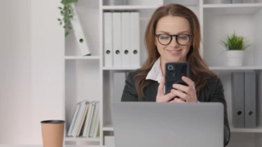 Business woman using phone in office at workplace The businesswoman is immersed in work, reviewing graphs and analyzing key business performance indicators. Views smartphone screen. High quality 4k
