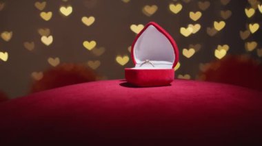 A precious jewelry gift for Valentines Day. A romantic surprise for Valentines Day. A gold wedding ring in a box as a symbol of love and wedding. Heart-shaped light on the background. High quality