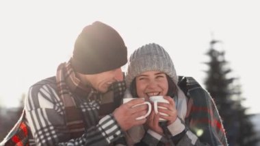 Peace and Love: A Winter Day Filled with Hot Tea and Tenderness in Your Arms. On a pensive snow-covered meadow, a couple shares the warmth of tea and washes each other in a quiet winter calm. High