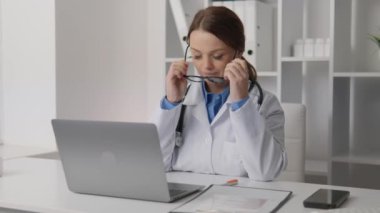 Doktor kadın yorgundu ve ellerini masasına yasladı. Yorgunluk ve yorgunluk, bir doktor olarak klinikte aşırı çalışma. Zor bir gün ve zor bir durum. Doktor onu çıkarıyor.