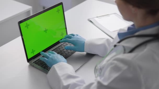 クロマキーテンプレート テーブル上のクリニックの緑色のラップトップスクリーン 効率性に焦点を当てた医師は 治療計画を正確に診断し 開発するために臨床データを使用します 高品質の4K映像 — ストック動画