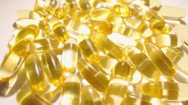 Vitaminli kapsüller ve yağ asitleri beyaz bir arkaplanda düzenlenmiştir. Şeffaf kapsüllerde sarı balık yağı izi var. Aktif bir yaşamı desteklemek için vitamin kapsülleri. Yüksek kalite 4k görüntü