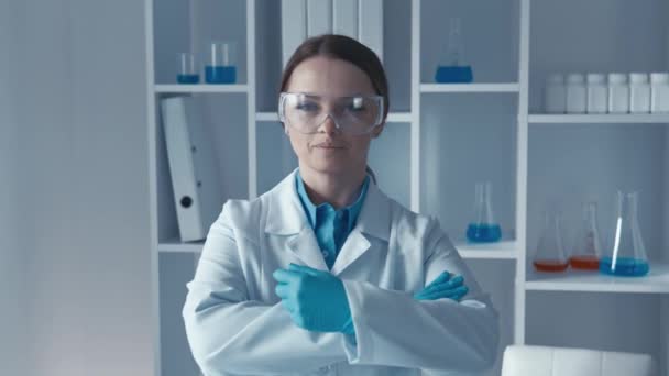 身穿化学防护服的妇女站在工作场所 寻找并摆姿势拍照 潜入一个实验室 在那里 一位科学家正在分析样本 以诊断疾病 高质量的4K镜头 — 图库视频影像
