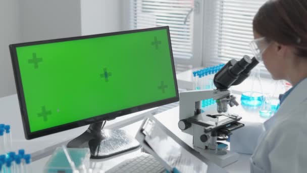 彩色键绿色屏幕 根据实验室的情况 化学家通过进行科学实验和医学实验来改进他的研究 在显微镜下 她研究分子的结构 — 图库视频影像