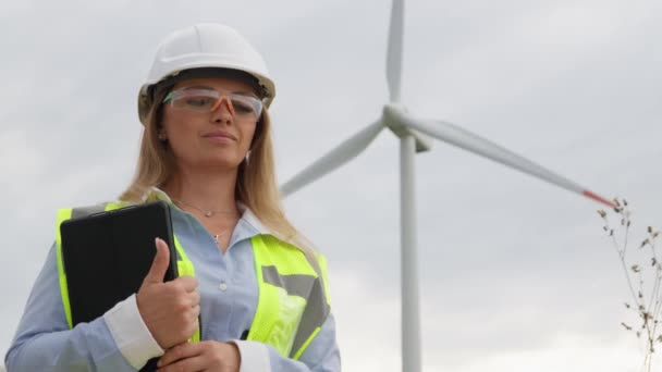 女性デザイナーは デジタル機器に依存して風力発電所の場所を慎重に計画しています 信号ベストとメガネの責任あるエンジニアは 発生する風車の農場を調べます — ストック動画