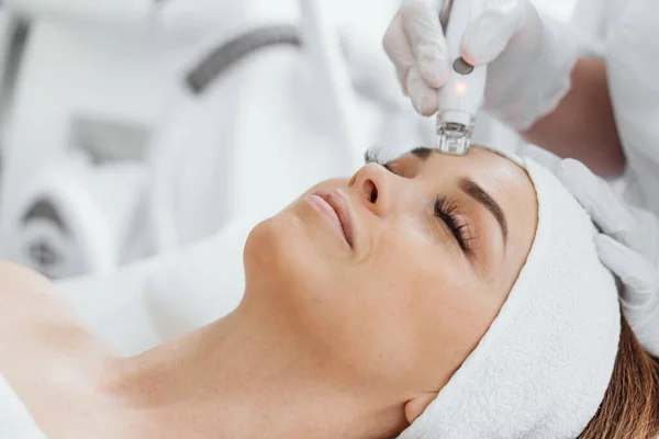 A professional esthetician uses the RF Lifting procedure to rejuvenate and tighten the skin of the clients face. Vacuum Facial Massage for Womans Skin Care. High quality photo
