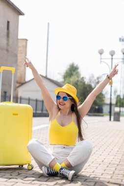 Eğlenceli bir hafta sonu: parlak görünümlü genç bir turist ayrılmaya hazırlanıyor. Şık bir tatil: Sarı elbiseli ve peronda bavullu bir kadın seyahat etmeden önce keyif alıyor. Yüksek kalite fotoğraf