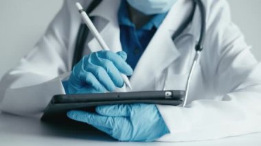 Çevrimiçi sağlık: bir kadın doktor dokunmatik bir tablete aktif olarak tıbbi göstergeleri analiz ederek yazar. Tıbbi teknoloji iş başında: doktor dokunmatik tabletteki verileri dikkatlice giriyor,