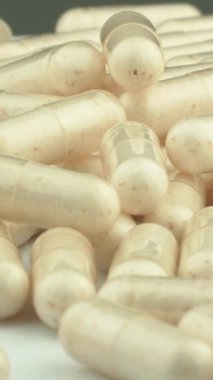 Beyaz bir zemin üzerinde dönen kapsüller, ilaç endüstrisinin ve sağlıklı bir yaşam tarzının sembolü haline gelir. C vitamini kapsülleri, sağlığı koruma potansiyelini açığa çıkarır. Yüksek