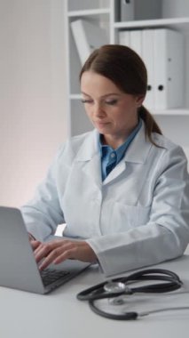 Steteskoplu bir doktor hastalarla etkileşim kurmak, danışmanlık yapmak ve tıbbi destek sağlamak için etkili bir şekilde dizüstü bilgisayar kullanır. Çalışıyor ve yüksek kalitede tıbbi hizmetler sağlıyor. Yüksek