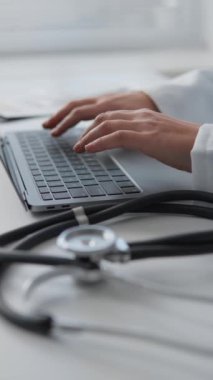 Klinikte dizüstü bilgisayarında çalışan genç bir bayan doktor hastaların tıbbi verilerini kaydediyor. Gülümseyen bir doktor, hastasına internetten danışmanlık yapıyor ve kaliteli tıbbi bakım sağlamak için yenilikçi teknolojiler kullanıyor.