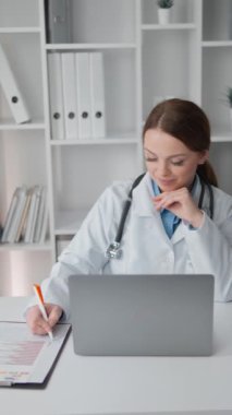 Bir sağlık uzmanı, hastaların muayene sonuçlarını dikkatle okuyor ve bilgisayar ekranında analiz ediyor. Tecrübeli bir doktor memnuniyet ifadesi ile danışmanlık yapar.