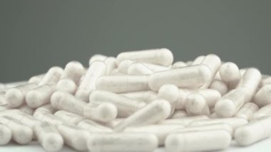 Vitaminli ve besin takviyeli beyaz kapsüllerin yavaş dönüşü sağlığın korunmasına yardımcı olur. Kapsüllerden alınan vitaminlerin güzelliği ve faydaları: kullanım kolaylığı. Eczacılık firması. Yüksek kalite 4k