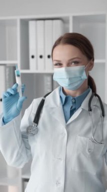 Tıbbi bir işlem yapmadan önce şırıngayı dikkatle inceleyen bir doktor, çalışmada hassasiyet ve dikkat gösteriyor. Doktor ilacı tavsiye ediyor, ilacın kalitesini gösteriyor.