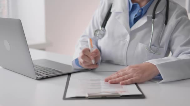 Kobieta Lekarz Pracująca Przy Stole Klinice Zapisująca Informacje Papierowej Tabliczce — Wideo stockowe