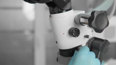 Diş mikroskobuyla dikkatlice gözlemleyen dişçi, hastaların dişlerini doğru bir şekilde muayene eder. Modern bir diş kliniğinde, modern teknolojiler bir doktorun işi. Yüksek