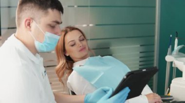 Diş hekimi, en uygun tedavi planını tartışmak üzere hastayla birlikte test sonuçlarını ve tanı testlerini bir tablette gözden geçirir. Yüksek kalite 4k görüntü