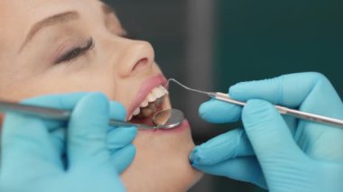 Kadın, dişçi koltuğuna dikkatle oturur ve dişlerini büyük bir özenle tedavi ederek acısız ve etkili bir tedavi süreci sağlar. Yüksek kalite 4k görüntü