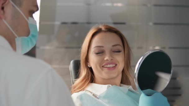 牙医向病人详细解释了治疗过程 强调了她微笑的改善 并在镜子中显示了结果 高质量的4K镜头 — 图库视频影像