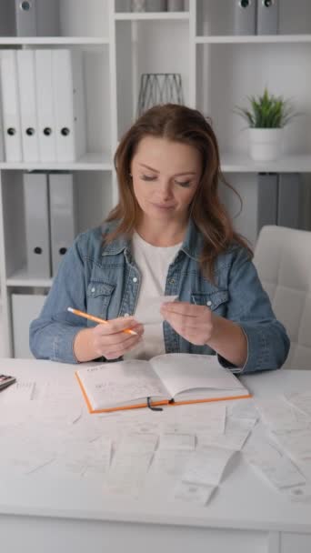 这个垂直的视频显示了一个女人仔细地计算和分析家里的开销 她专注于自己家里的文书工作 用计算器有效地管理家庭预算和账单 — 图库视频影像