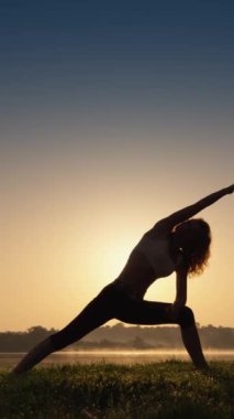 Yoga pozu veren bir kadın, sabahları güneş ışığının tadını çıkarırken zihinsel sağlığını ve canlılığını geliştirir. Yüksek kalite 4k görüntü