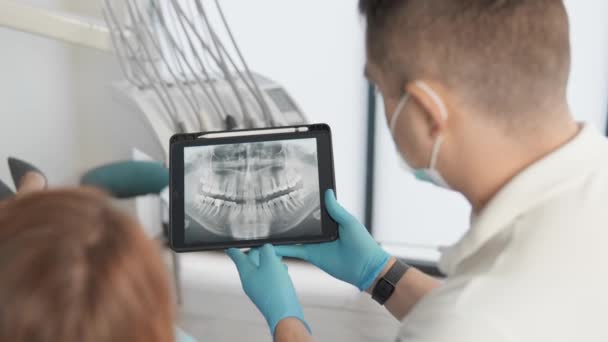 平板电脑的屏幕显示了X光和诊断图像 牙医向女病人解释了这些图像 以便更好地了解她的健康状况 高质量的4K镜头 — 图库视频影像