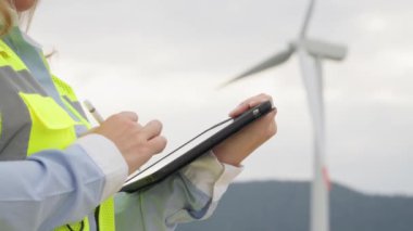 Dijital tabletli bir mühendis rüzgar türbinleri kullanmanın sonuçlarını analiz ederek enerji sistemlerini optimize etmek için yenilikçi yaklaşımlar sunuyor. Yüksek kalite 4k görüntü