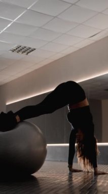 Spor salonunda bir kadın etkileyici bir beceri ve esneklikle fitbol egzersizleri yapar. Odaklanması ve esnekliği korse kaslarını çalıştırmasına ve direncini geliştirmesine yardımcı oluyor. Yüksek kalite 4k görüntü