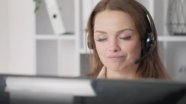 Uzak bir ofiste çalışan bir kadın destek danışmanı müşterilere telefonla güvenilir ve dostane bir destek sağlıyor. Mesleki yaklaşımı şirketle etkileşimi hoş kılıyor.