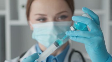 Elinde şırıngayla yeni bir aşı tutan bir tıp araştırmacısı klinik deney aşamasına hazırlanıyor ve olası faydaları ve riskleri inceliyor. Eczacı şırıngayı kolayca steril bir şırıngaya yerleştiriyor.