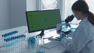 Krom anahtar yeşil ekran, kadın bilim adamlarının çalıştığı kimya laboratuarındaki bilgisayar monitöründe. Faimatsevt mikroskopta inceler. Bir biyolog, bir doktor, testleri inceler. Aşı