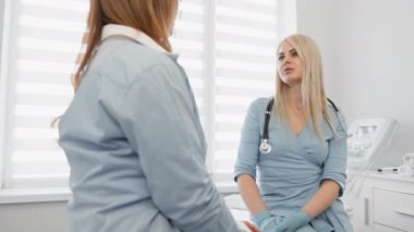 Steteskobu olan kadın bir doktor bir kadın hastaya danışmanlık yapıyor. Ayarlar, hasta bakımı ve iletişimine odaklanmış profesyonel bir sağlık ortamını gösteriyor.
