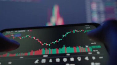 Akıllı telefon ekranı ile etkileşime giren parmaklar canlı borsa verilerini canlı renkler ve grafiklerle göstererek gerçek zamanlı finansal ticaret ve analizleri gösteriyor..