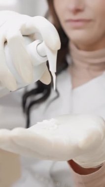 Görüntü, eldivenli ellerin dikkatli bir şekilde krem sürmesini, klinik, profesyonel ya da güzellik ortamında hassasiyet ve temizlik sağlamasını, hijyen ve doğruluğu vurgulamasını temsil ediyor.