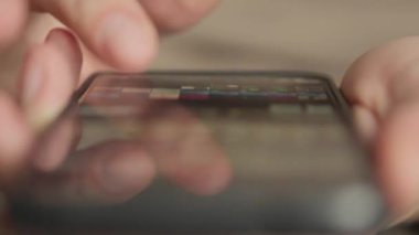 Akıllı telefon dokunmatik ekranı ile etkileşen makro parmak görüntüleri. Eller kapalı bir ortamda gezinme, mesajlaşma ya da uygulama kullanımının göstergesi olan mobil bir cihazda gezinirken görülüyor.